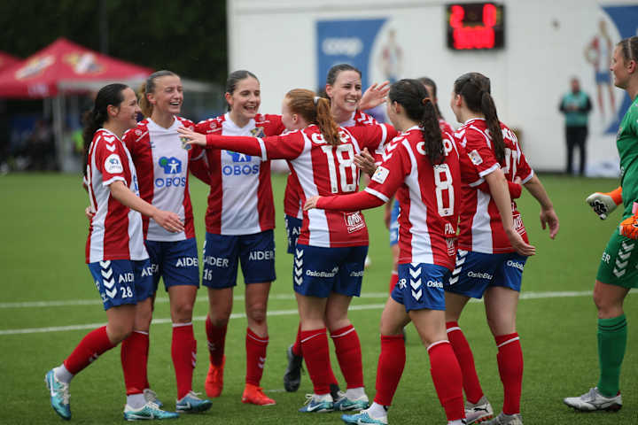 Foto av Lyn Damer som klemmer hverandre på banen under en fotballkamp.