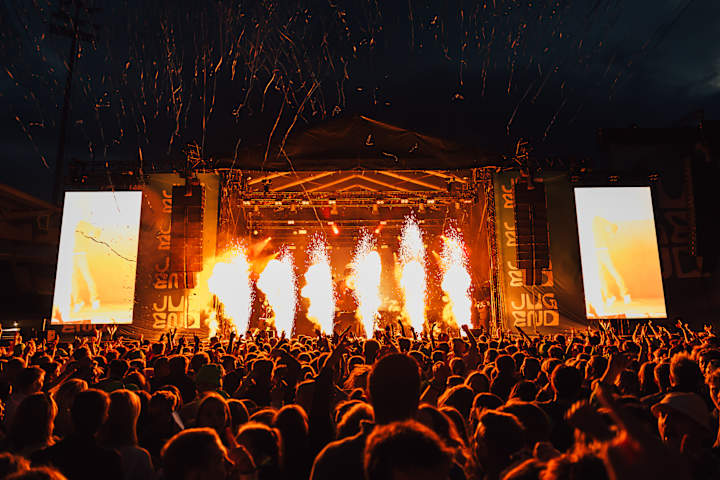 Foto av scenen under Jugend fest om natten med pyro som lyser opp mørket.