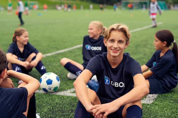 Fire fotballjenter står ved siden av hverandre og jubler med hendene i været. Hun ene holder en fotball i ene hånda.