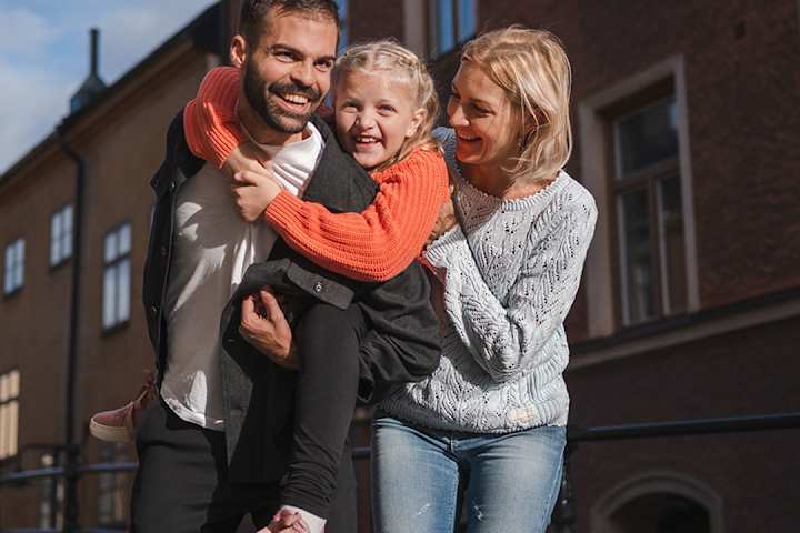 Familj med dottern på ryggen på sin pappa