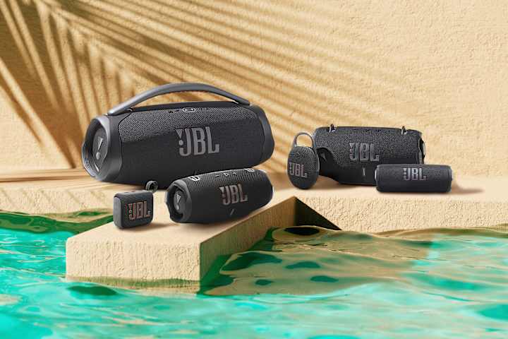 Flere ulike JBL høyttalere står oppstilt ved et vann.