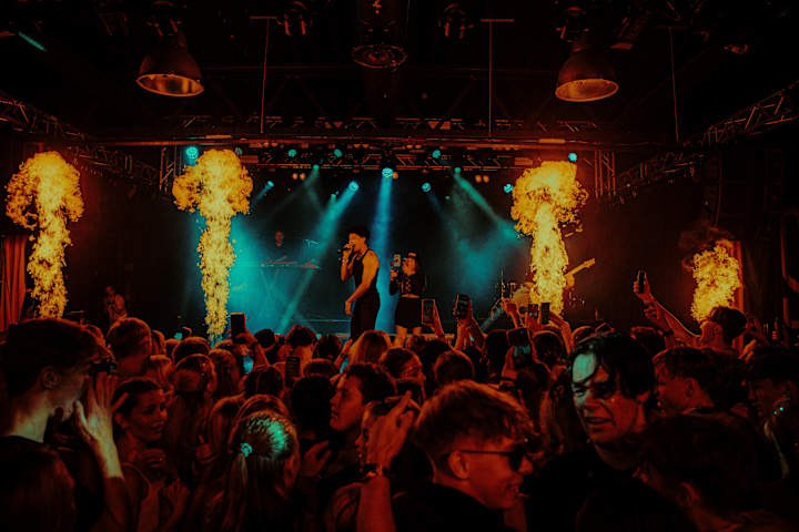 En artist står på scenen og synger under en konsert.