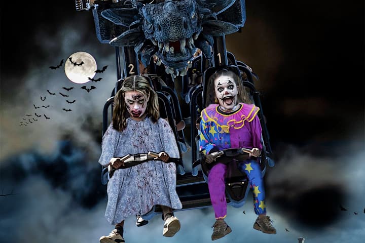 To jenter sitter i en karusell og har kledd seg ut. Det er Halloween og ser skummelt ut.