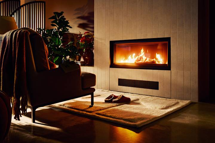 En stol med et pledd over står foran en vedpeis