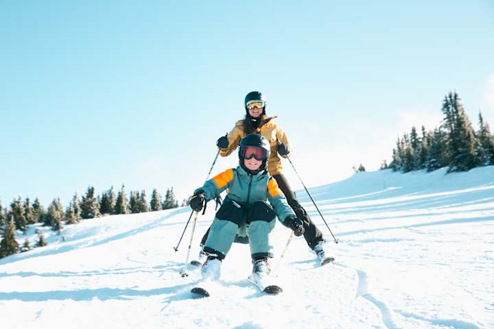 En gutt kjører slalom nedover mens en kvinne kjører hakk i hel.