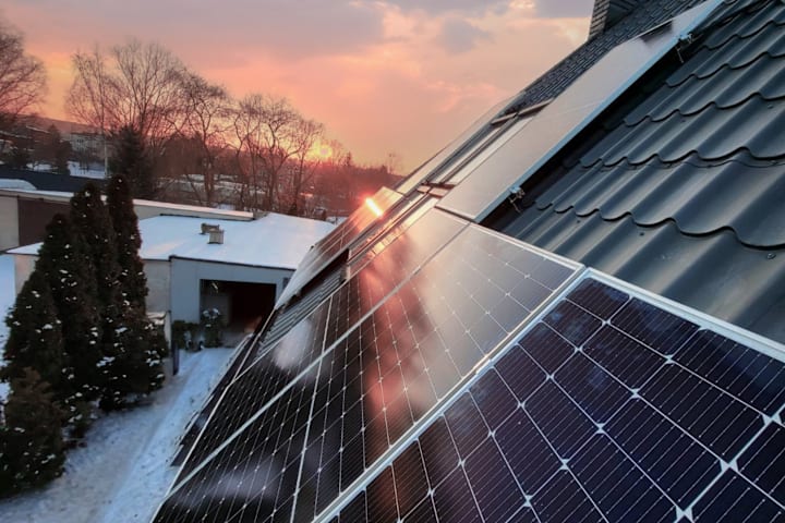 Et bilde av solcellepanel på tak om vinteren. Det er solnedgang,