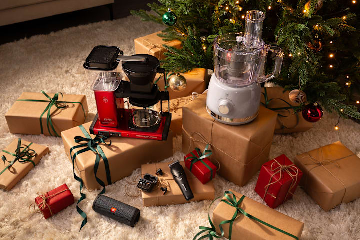 Illustrasjonsbilde av ulike produkter som både er pakket inn og ikke. De ligger under et juletre. Du ser blant annet en Moccamaster.