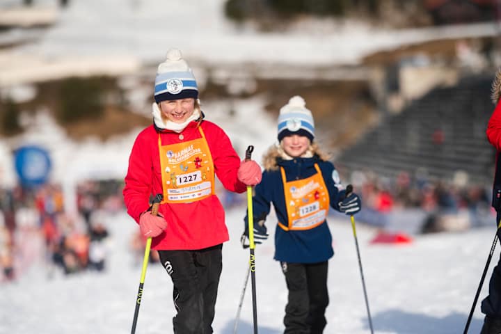 To barn har ski på beina og klemmer en grønn elg.