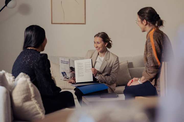 Visningsskilt i hånden til megler som står på terrasse med frodig plen foran