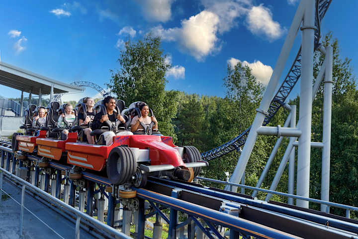 Det sitter flere glade ungdom i speedmonster-karusellen og smiler. Karusellen har akkurat stoppet.