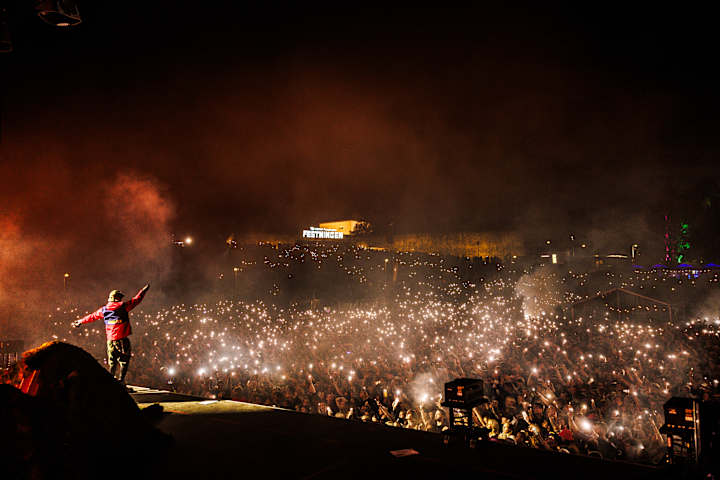 Bilde tatt fra festivalscenen på Festingen. Artisten i forgrunnen ser utover folkehavet i natten.