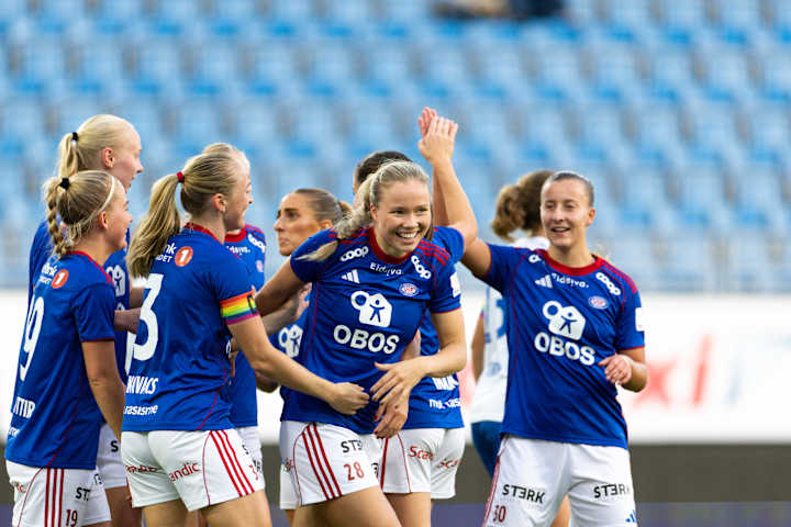 Foto av åtte spillere fra Vålerenga Kvinner som jubler sammen på fotballbanen. De feirer tilsynelatende en scoring.