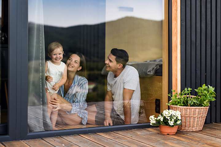 En dame og en gutt putter ved i en peis. Du ser lyset fra flammene. De smiler.