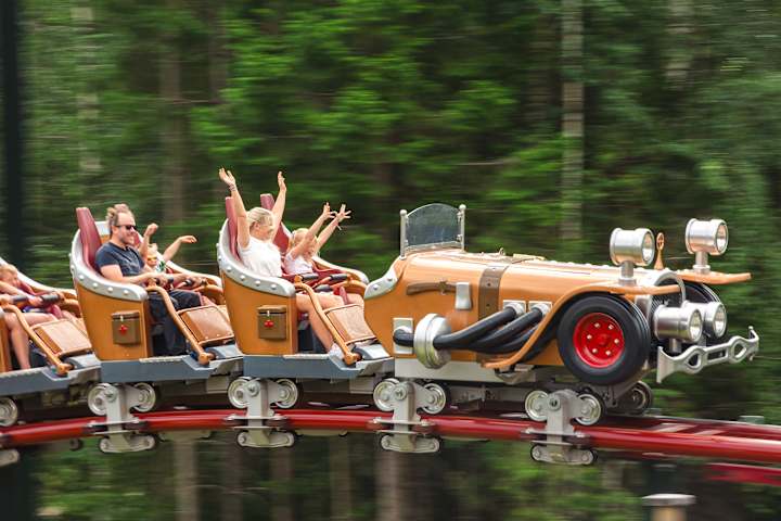 Flere mennesker sitter i en karusell. De har armene opp.