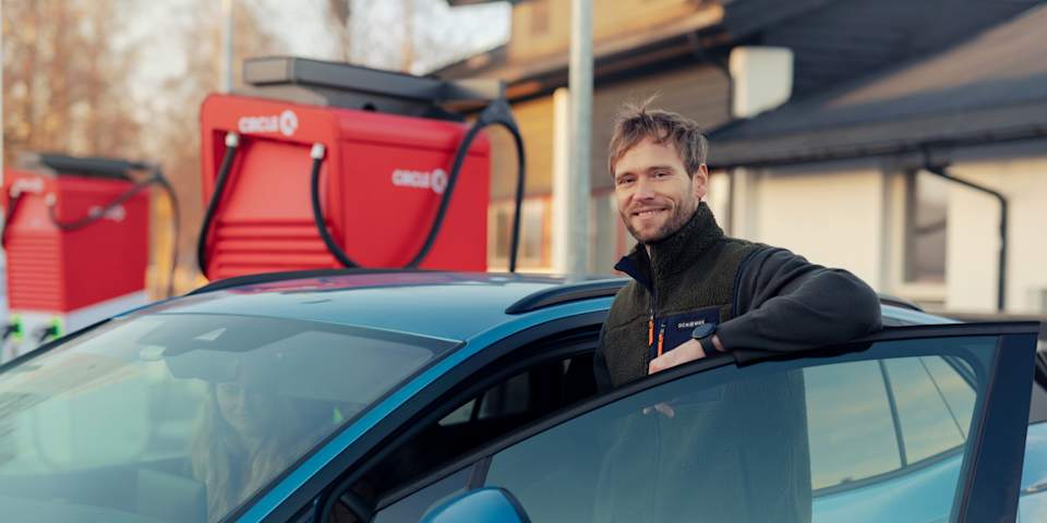 En mann lener armen sin på bildøra og smiler. Han er på vei avgårde fra Circle K.