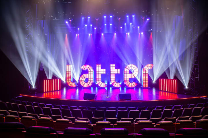 Bilde av Latter sin logo på hovedscenen, som lyser opp av ulike lys