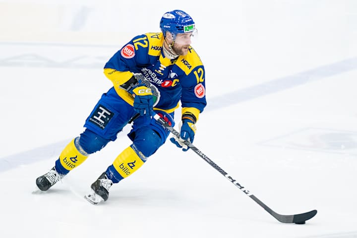 Ishockeyspiller i aksjon på banen i gul drakt