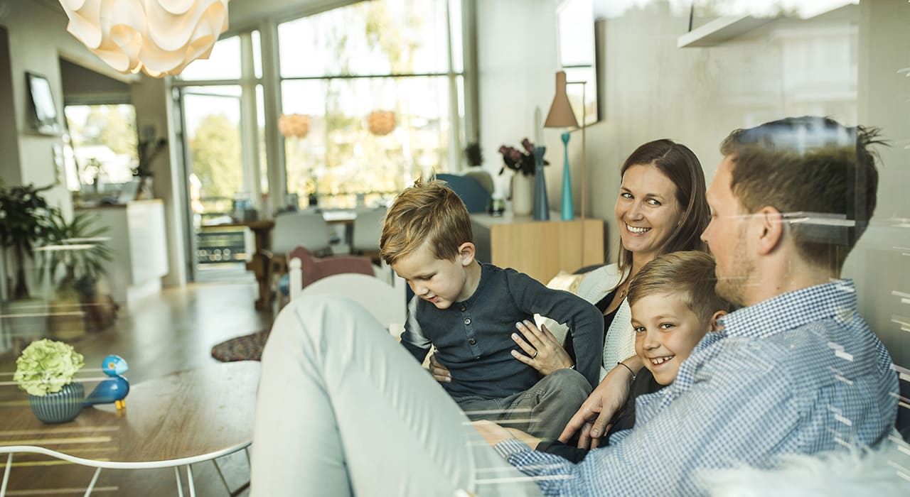 to voksne og to barn i godt humør sitter i en sofa