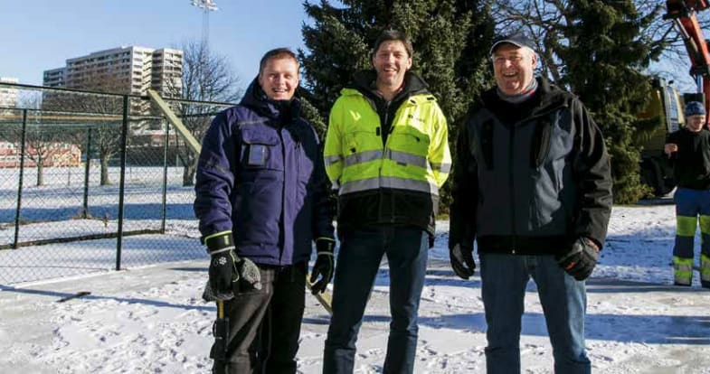 Bilde av tre menn som står utendørs i snøen og smiler