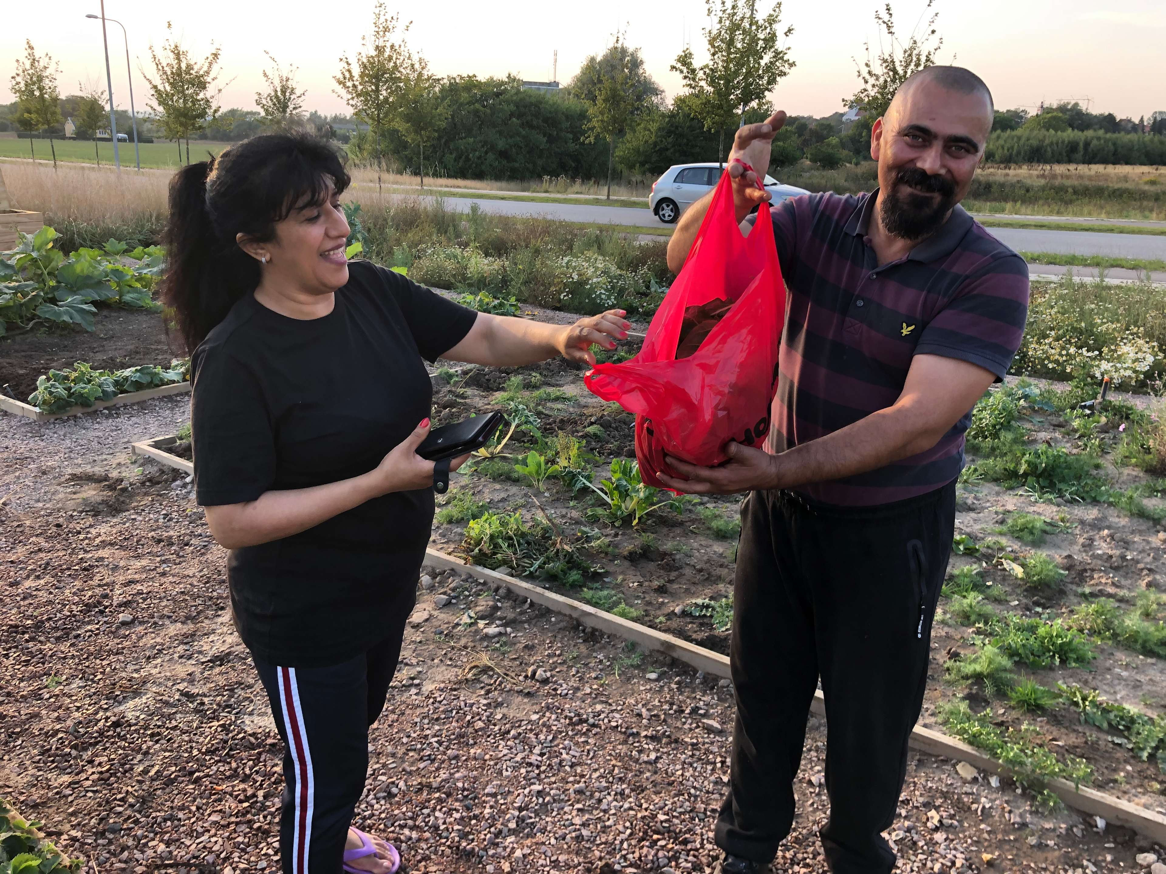 En tjej och en kille visar stolt upp sina grödor