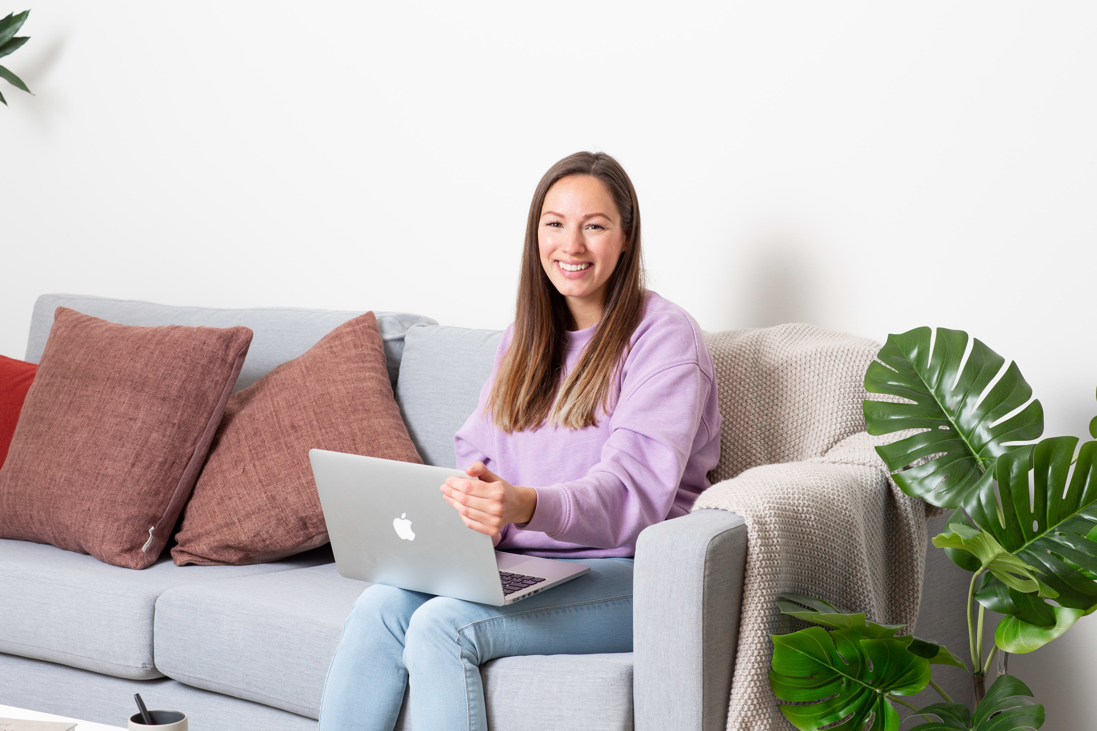 Ung kvinne i sofa med laptop