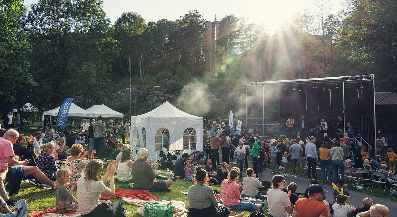 Konsert med publikum foran scenen og sittende på en slette foran.