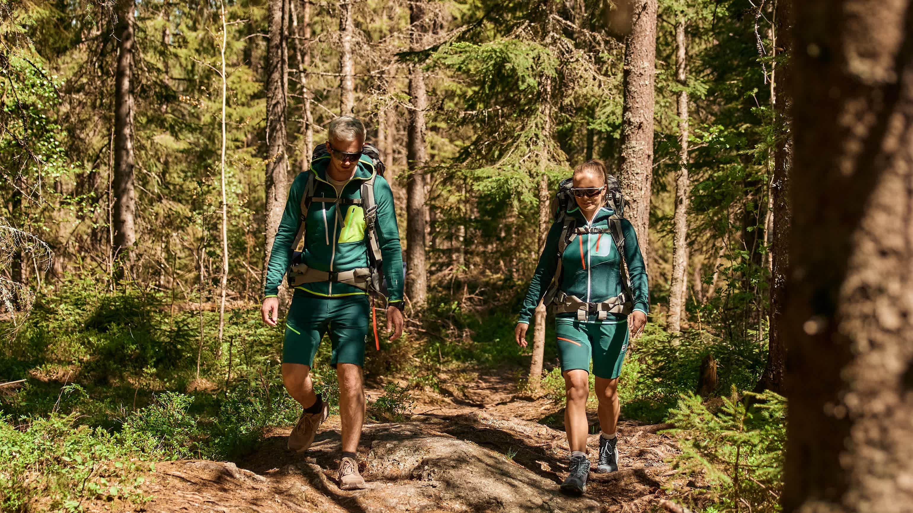 Et par går i skogen og har gode treningsklær og sekker.