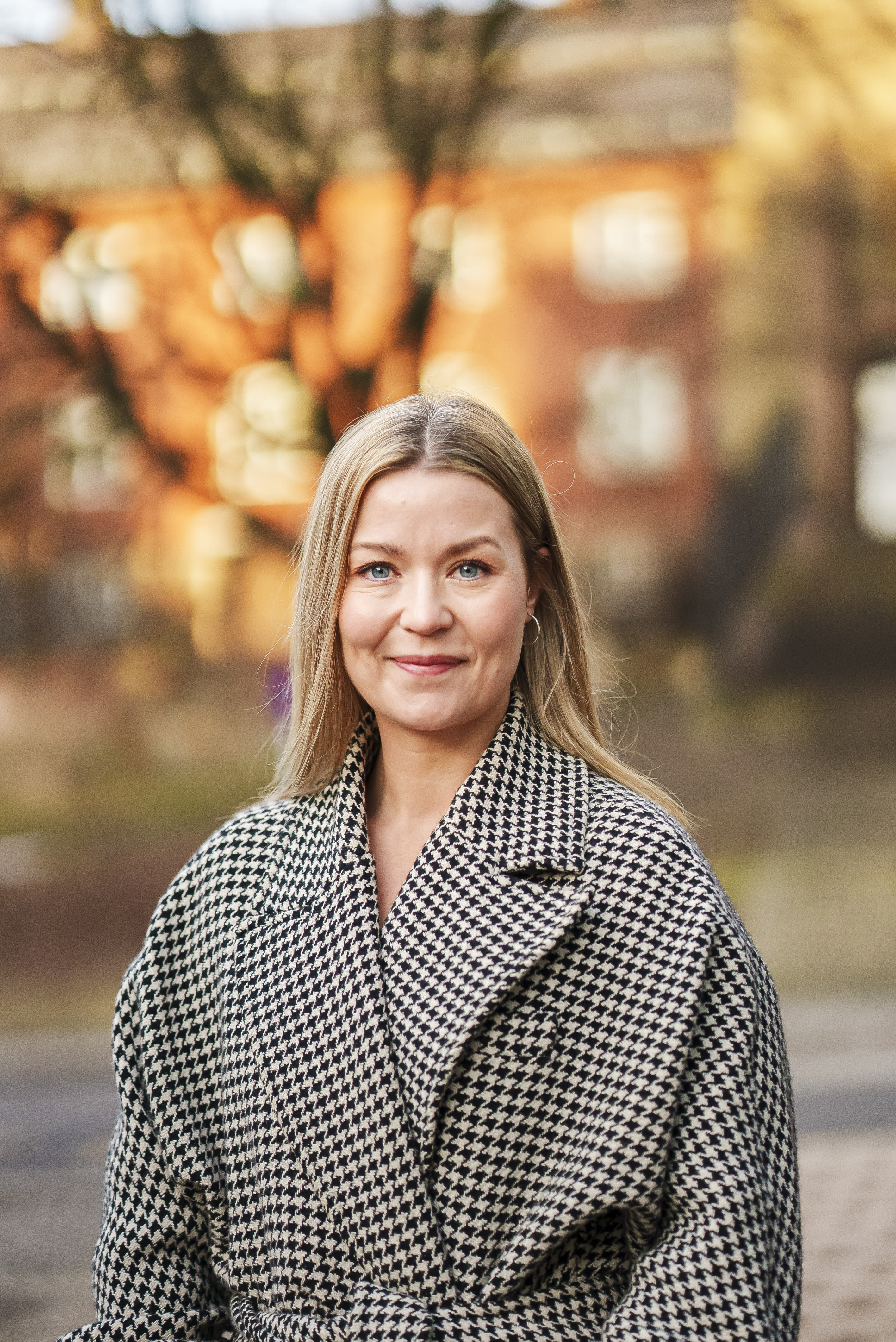 Bilde av Tonje Hovde Skjelbostad, advokat og daglig leder i advokatfirmaet Legalis. Hun har på seg en kåpe. Det er høst ute og hun smiler.