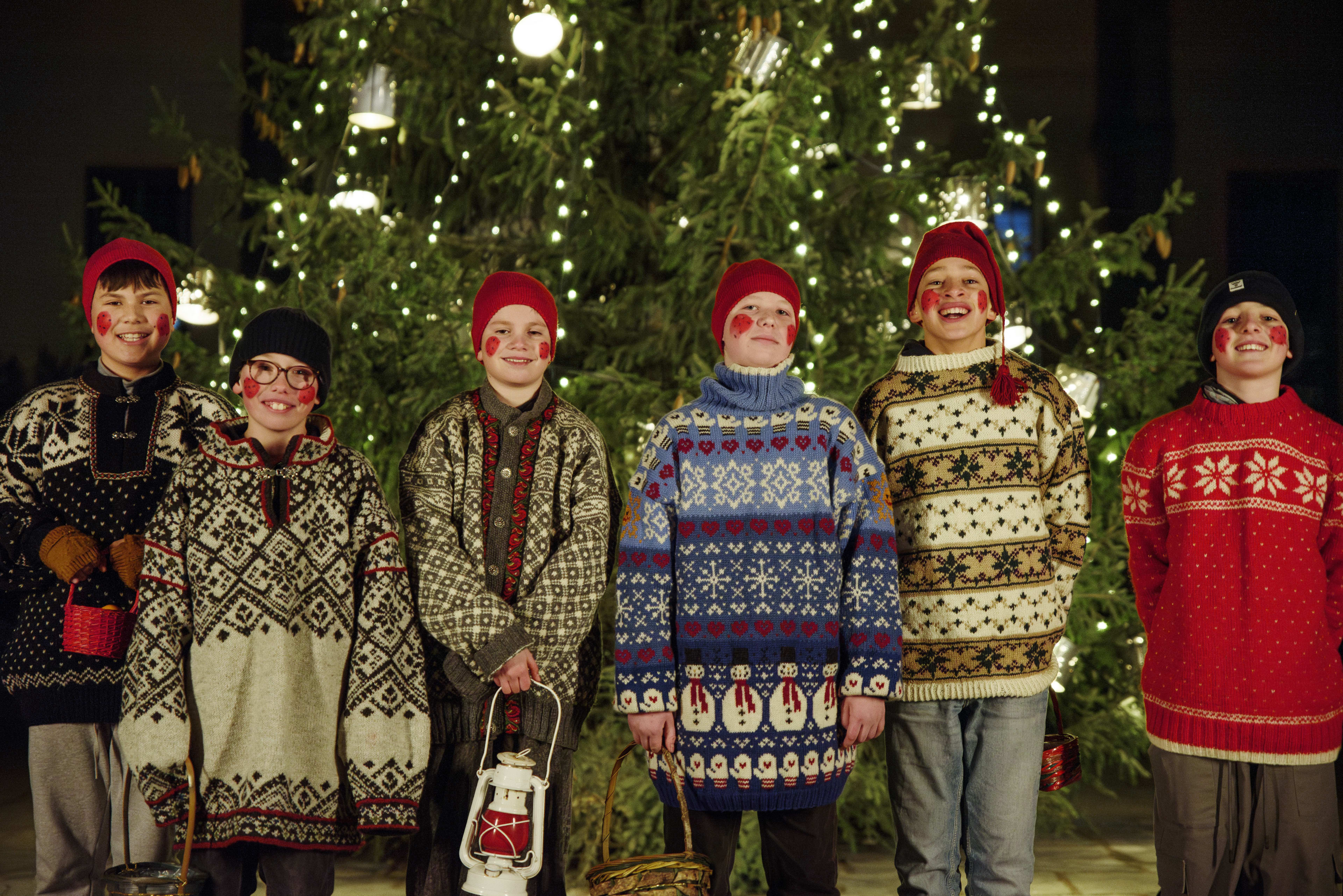 Julebukker kledd i julegensere foran et juletre.