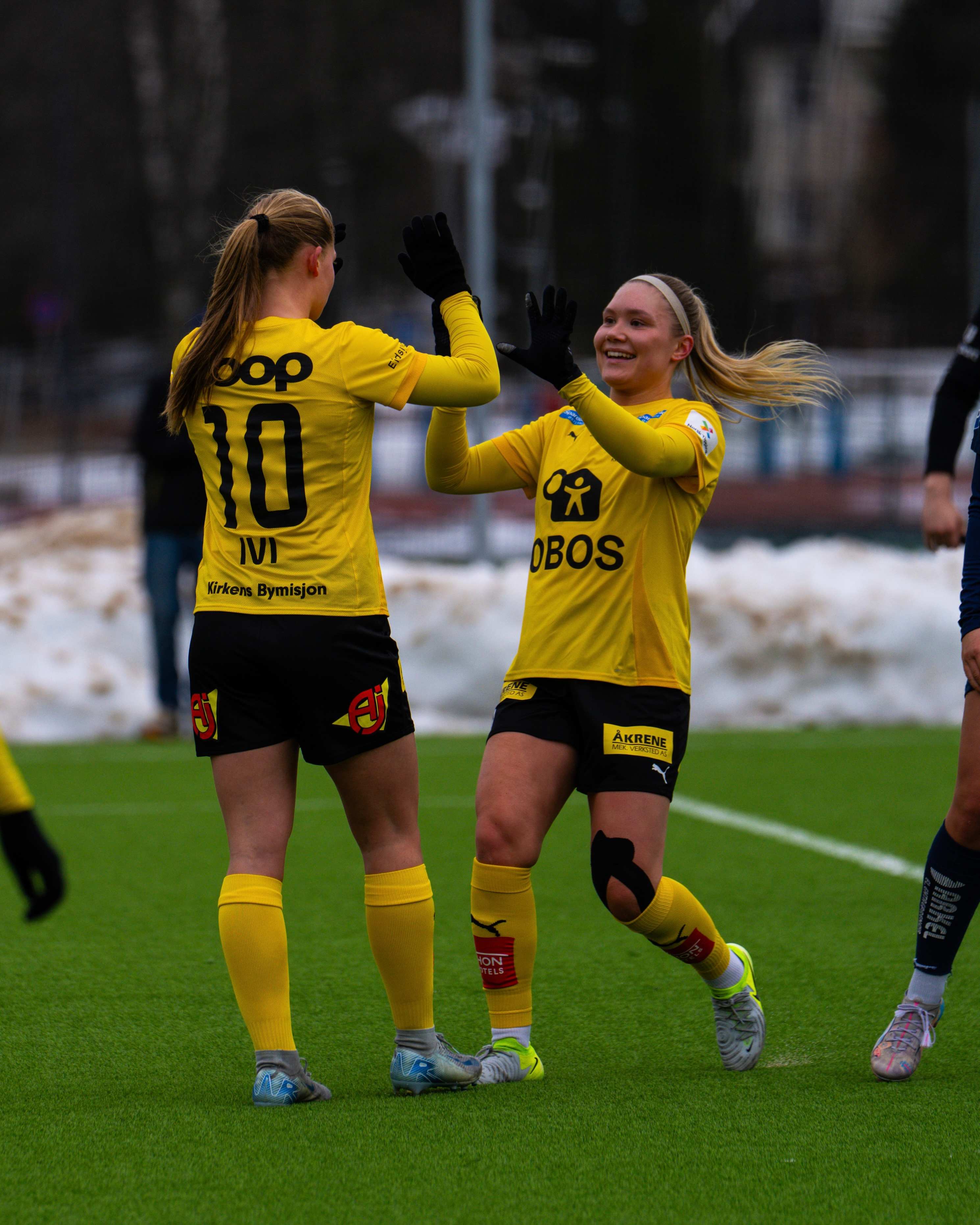 Foto av to LSK Kvinner spillere som tar high-five på banen.