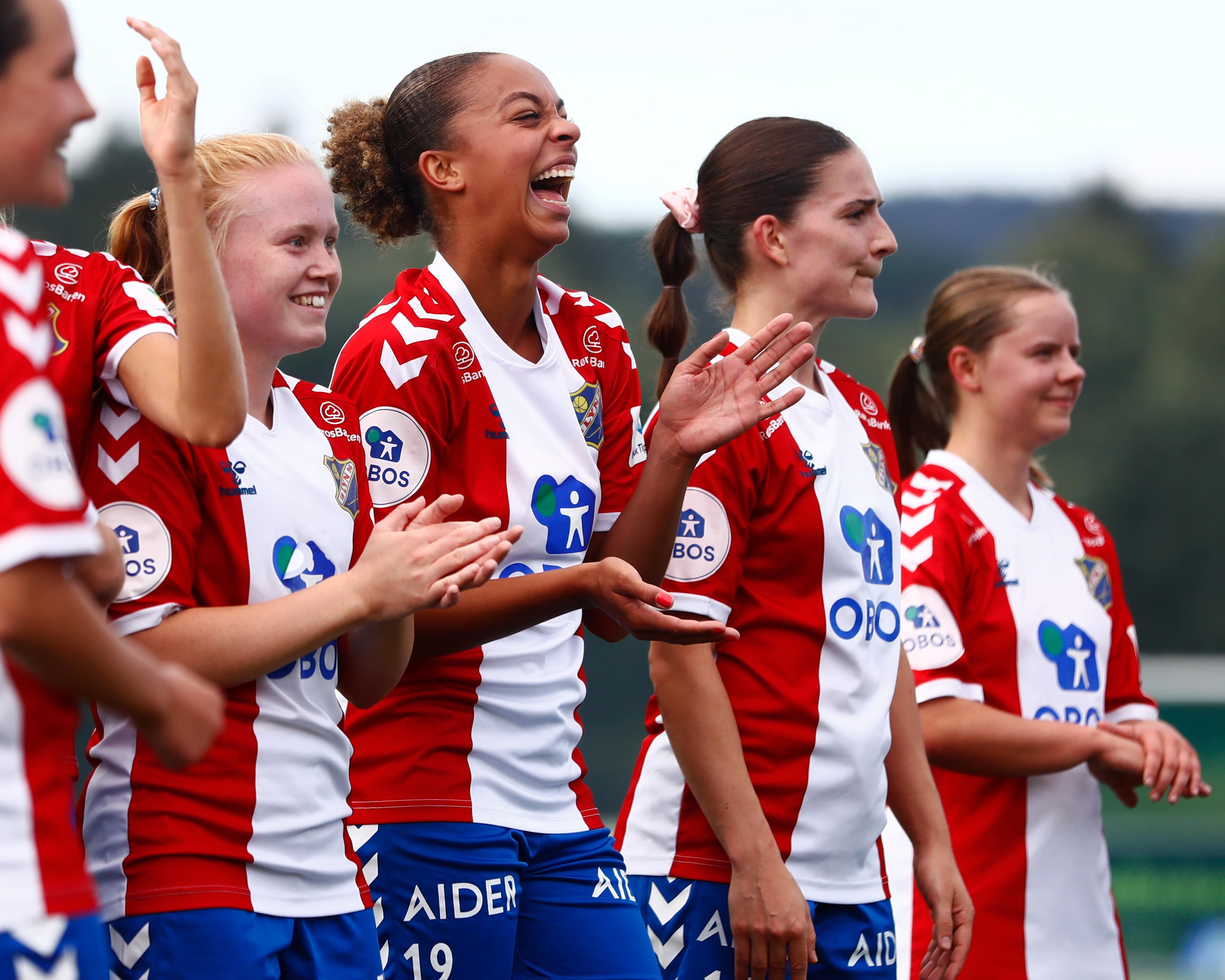 Foto av Lyn Damer spillere som står på rekke og klapper og smiler.
