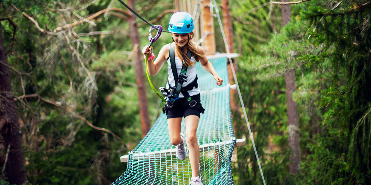 En jente klatrer i klatreparken Høyt & Lav