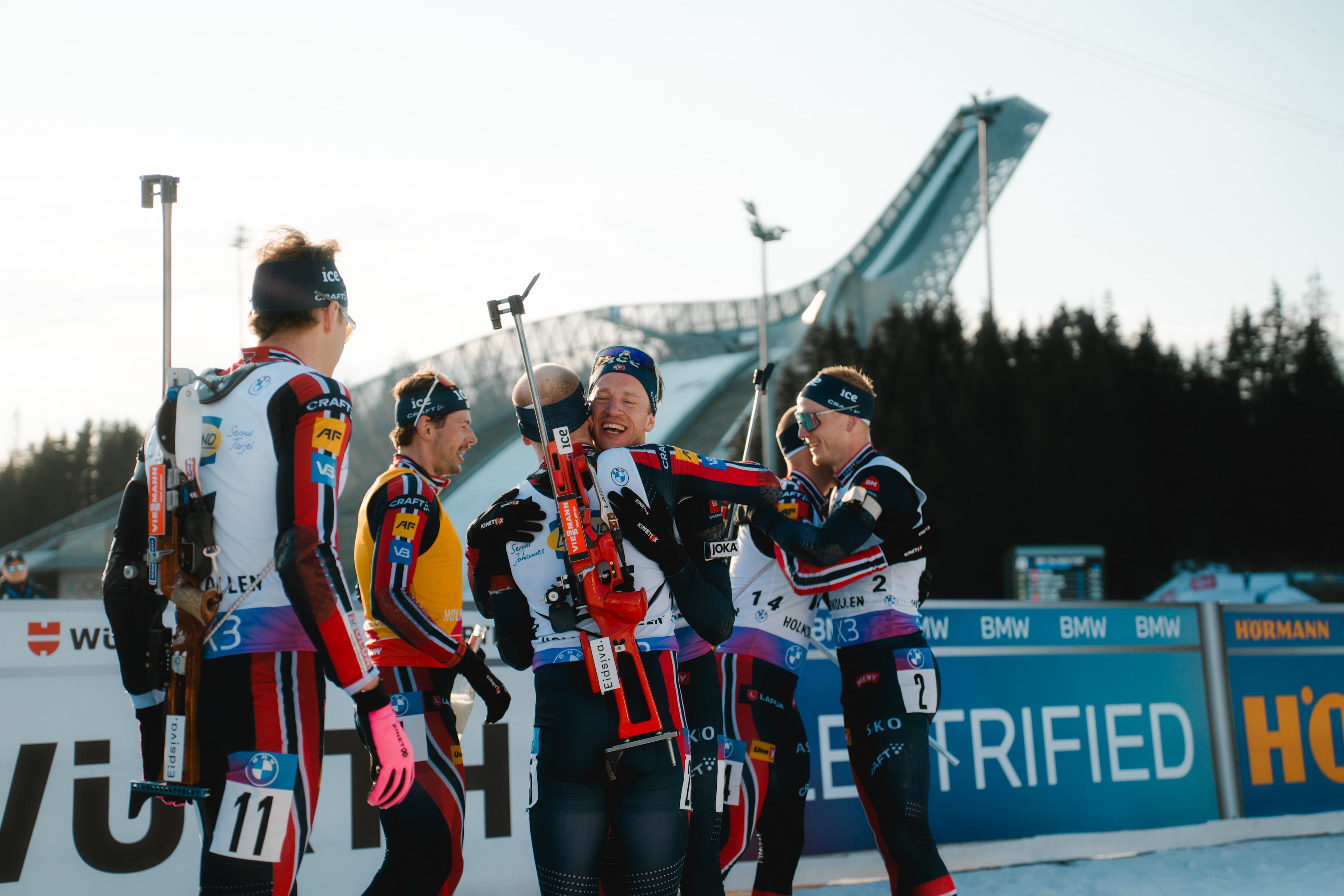 Skiskytterne til Norge feirer sammen etter å ha passert målstreken.