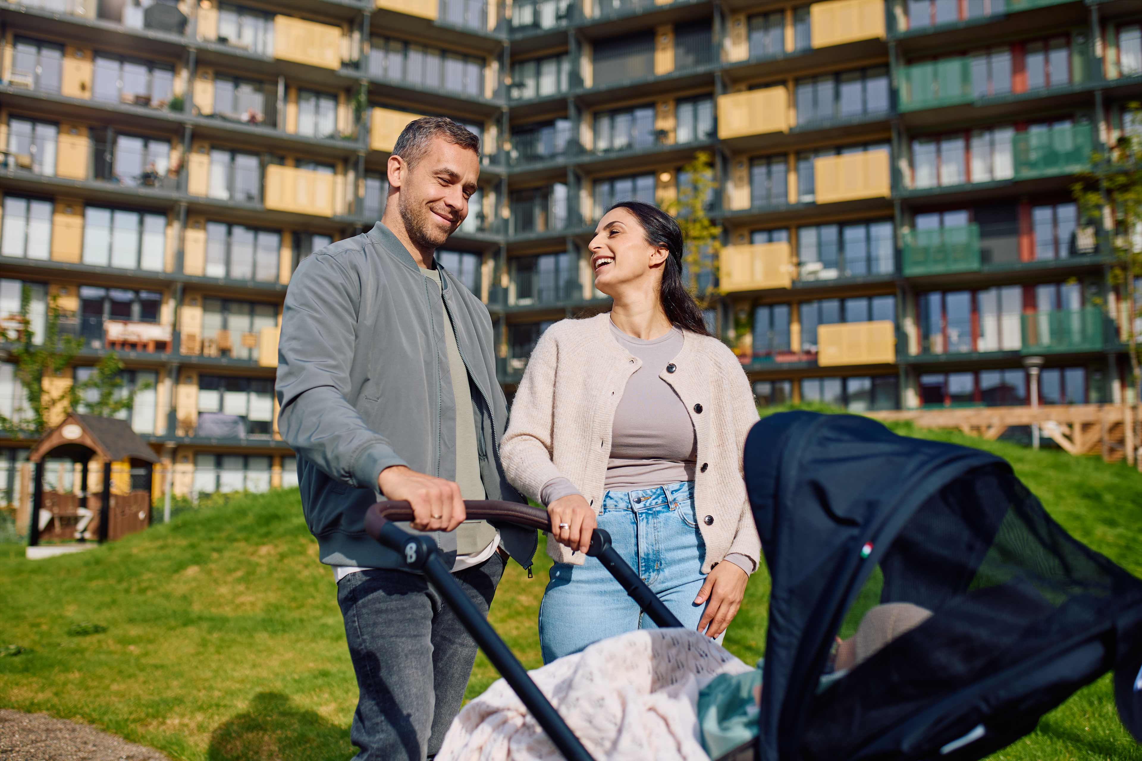 Et par triller en barnevogn utenfor blokker, De smiler.