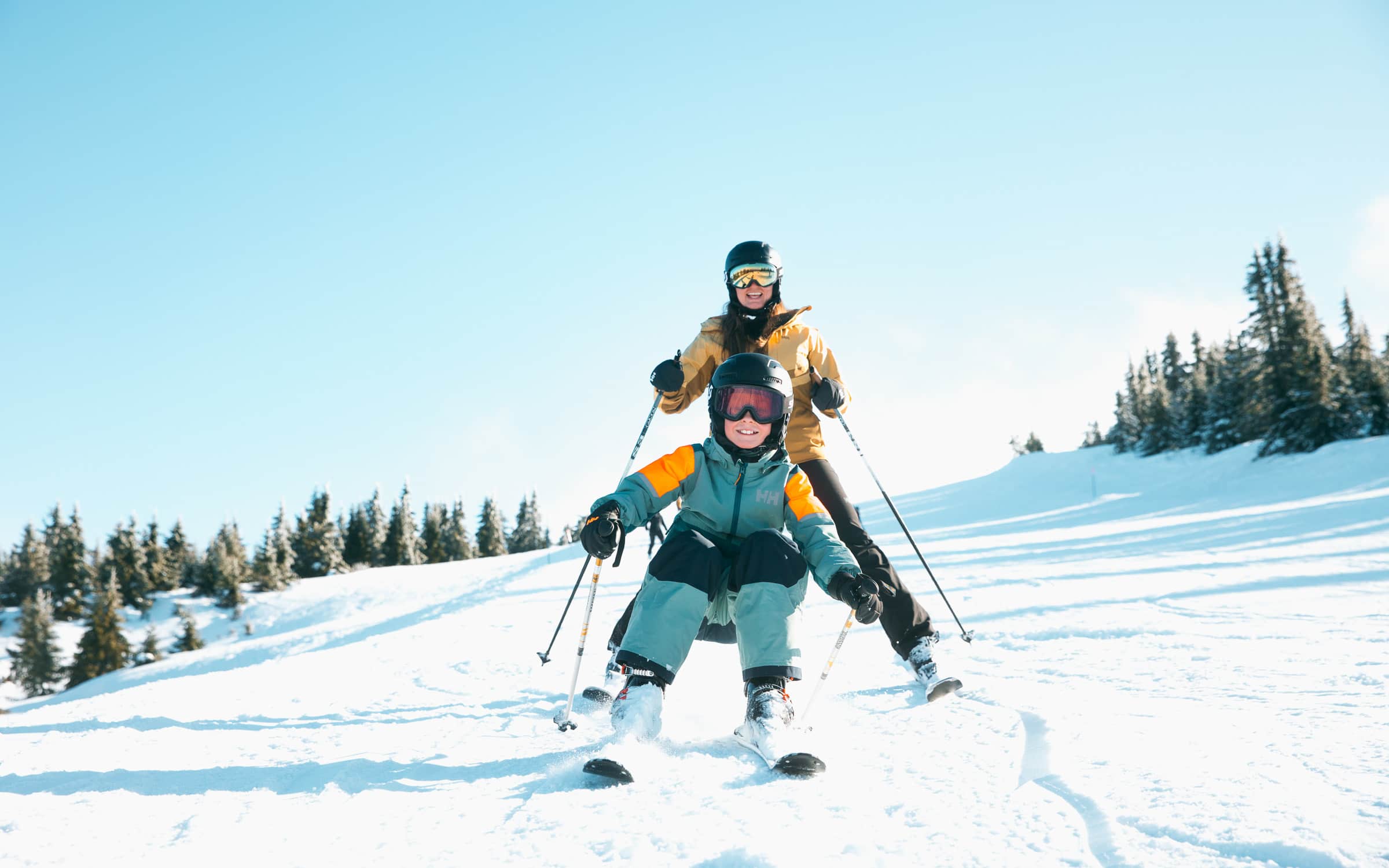 En gutt kjører slalom nedover mens en kvinne kjører hakk i hel.