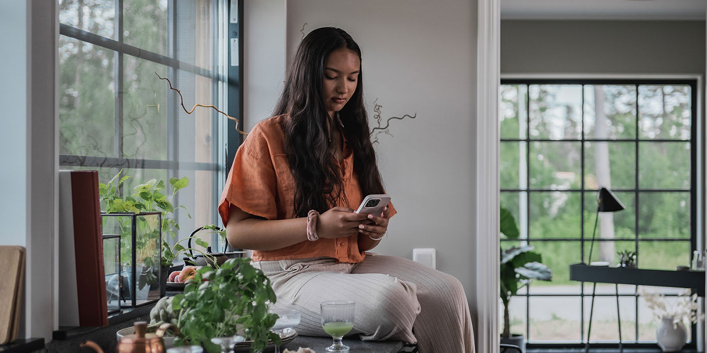 Tjej som sitter på köksbänken och tittar på mobilen