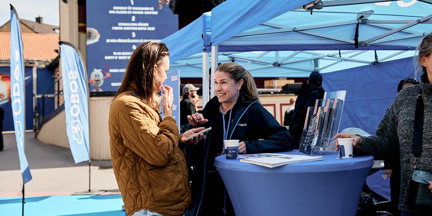 Medlem som pratar med OBOS-personal i OBOS-tältet