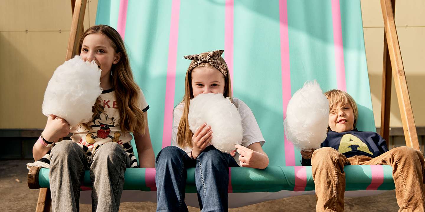 Barn som äter sockervadd sittandes i en superstor solstol