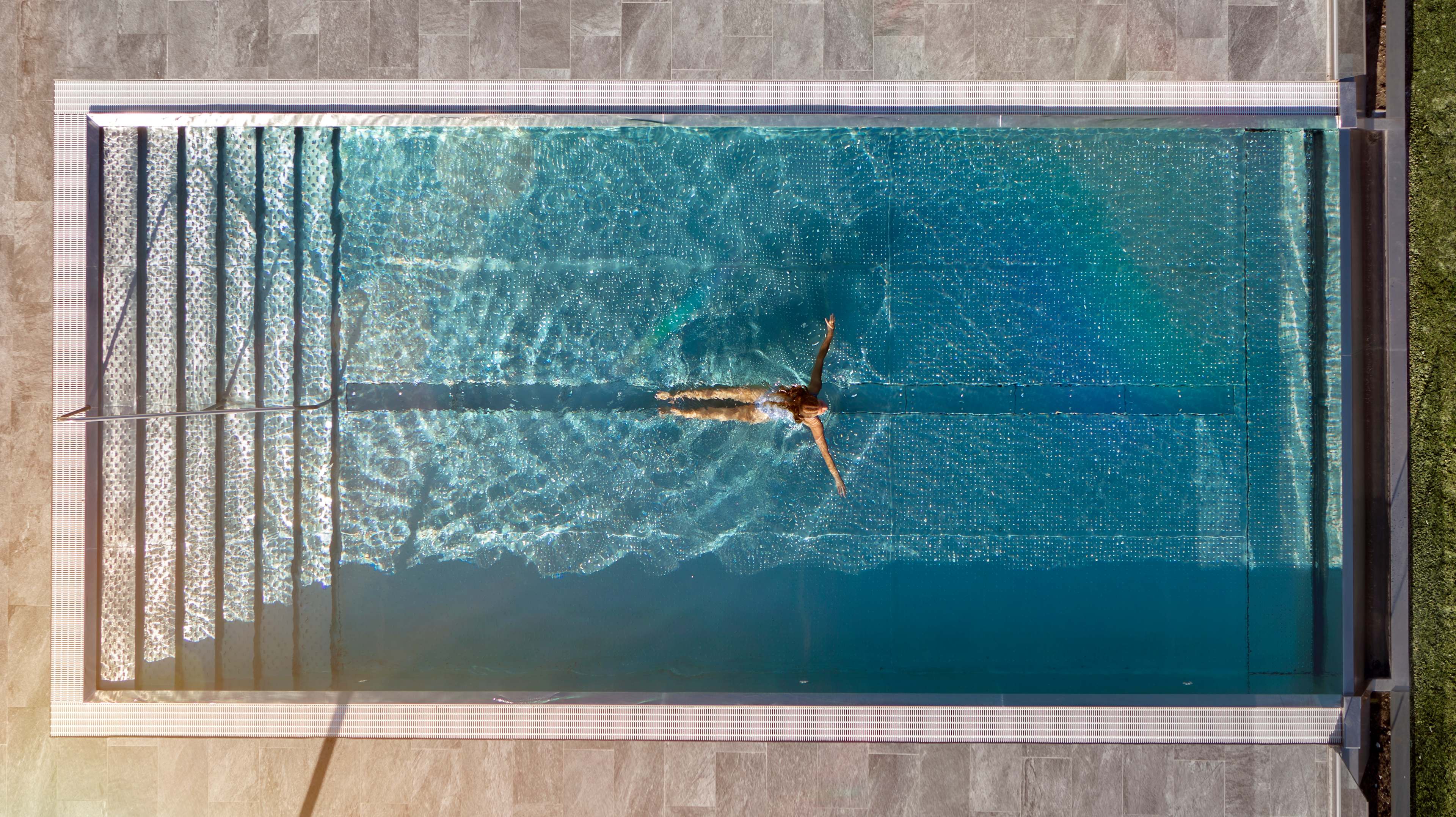 Bilde av en dame som bader i et utebasseng på hotell og ligger som en T i vannet.