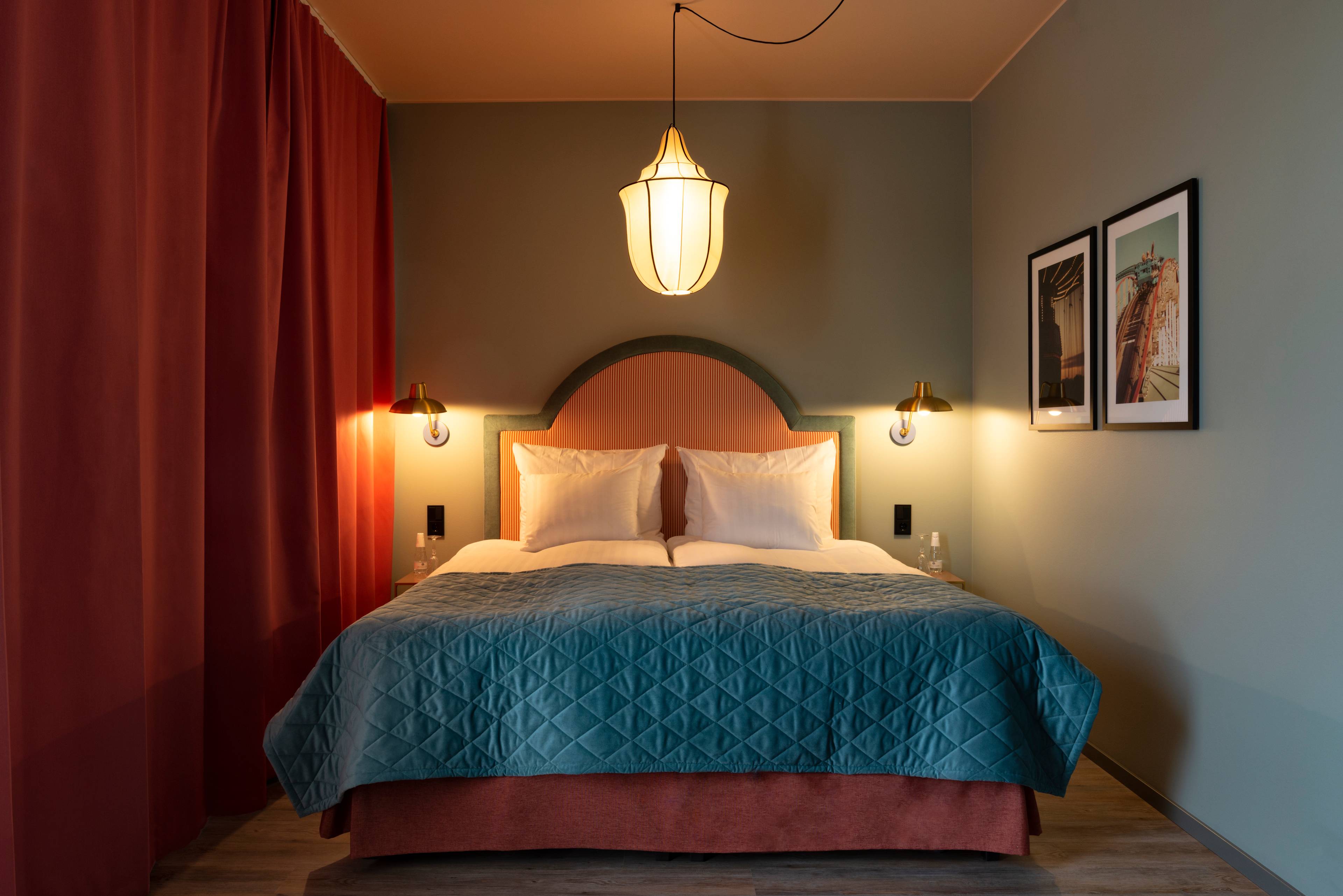 Du ser et nydelig rom med dobbeltseng, pastellfarger og lampe i taket.