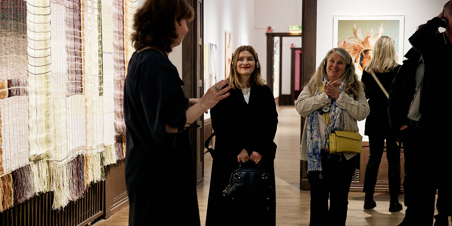 Två medlemmar som står och lyssnar på guiden