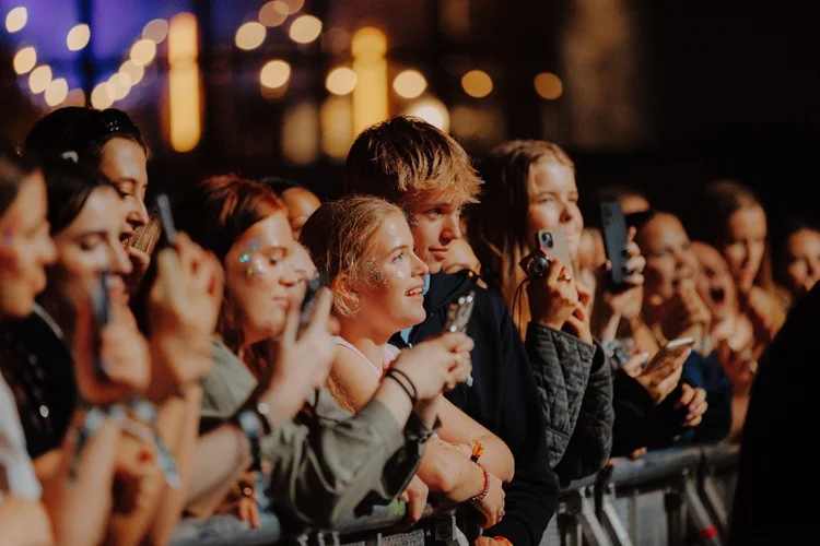 Nærbilde av publikum helst framst mot scenen på Spirefest. Flere holder opp telefonene sine har filmer eller tar bilder.