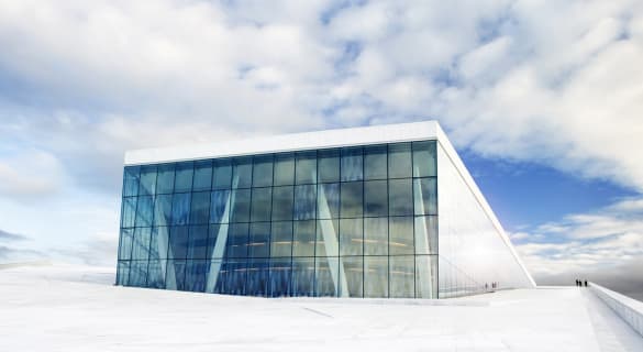 Operahuset i Oslo sett utenfra mot blå himmel og skyer.