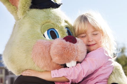 Liten jente klemmer kanin-maskot på Liseberg