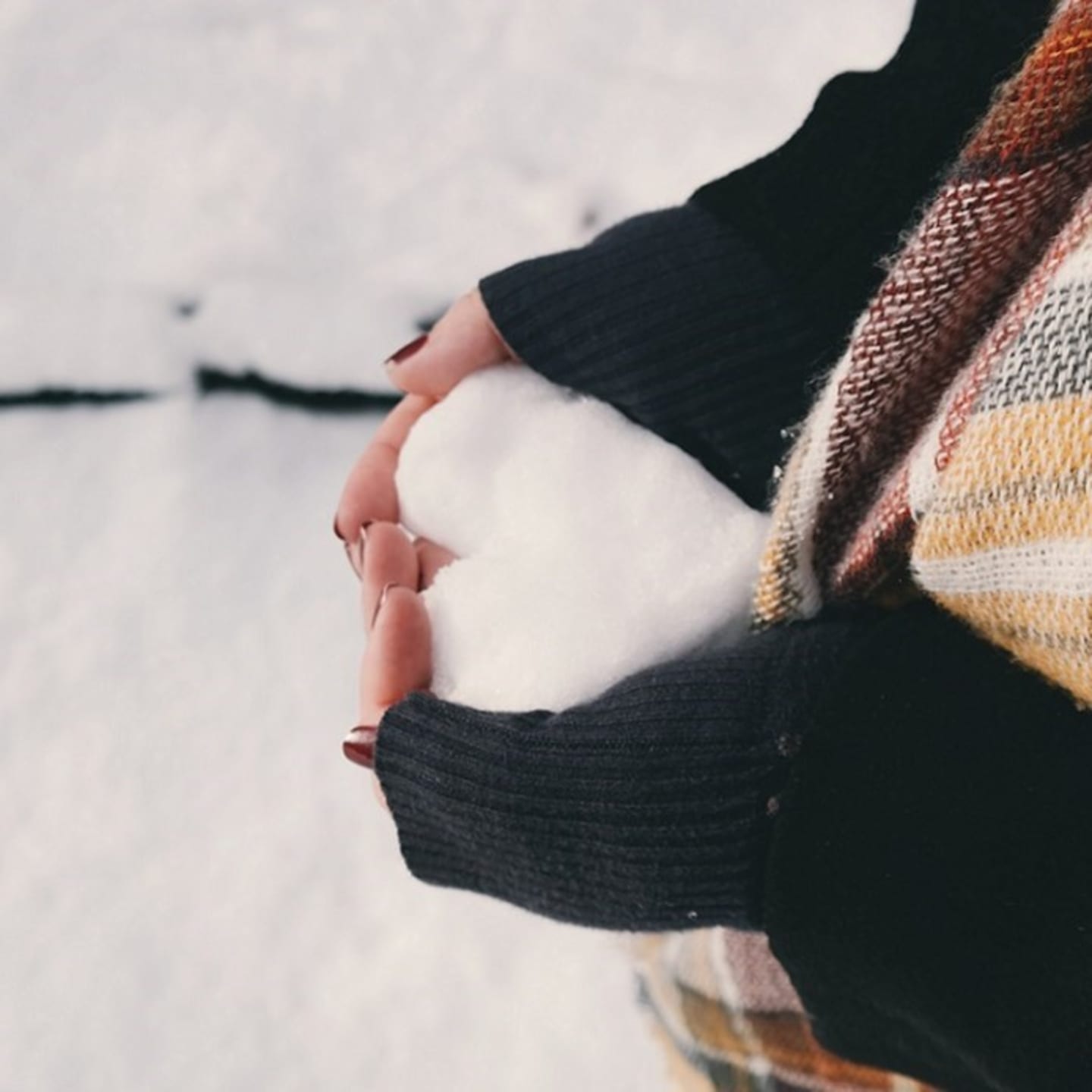 En person holder et hjerte formet av snø. Foto.