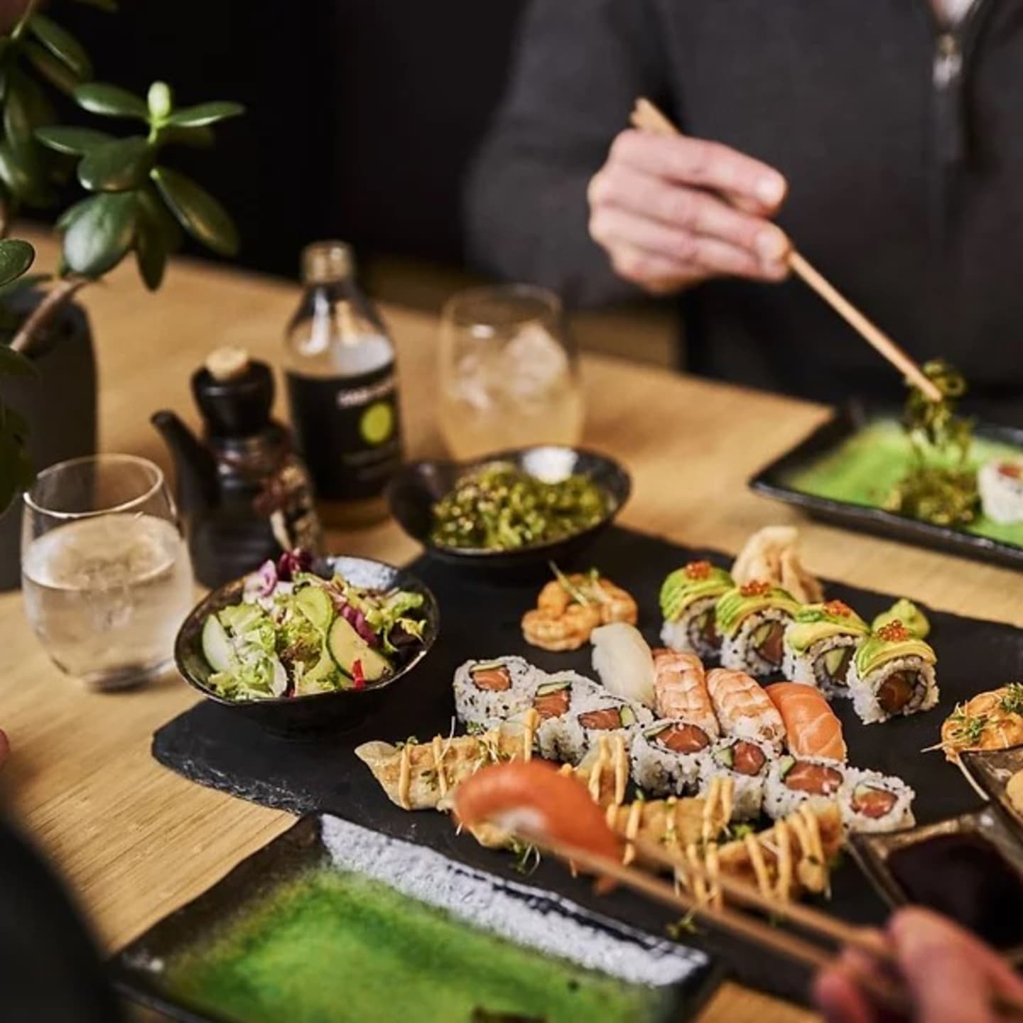 To personer  som sitter ved et bord og spiser ulike typer sushi