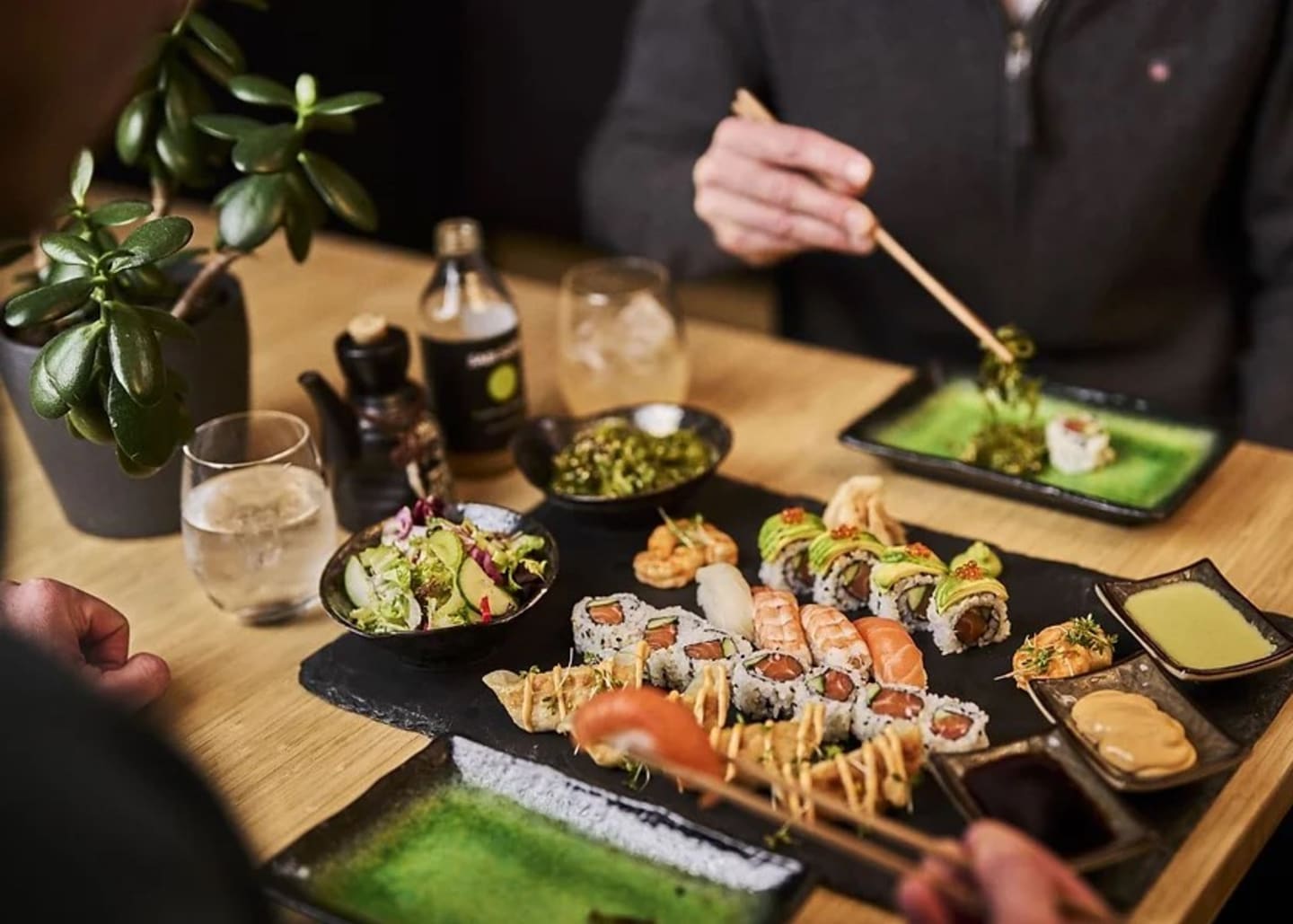 To personer  som sitter ved et bord og spiser ulike typer sushi