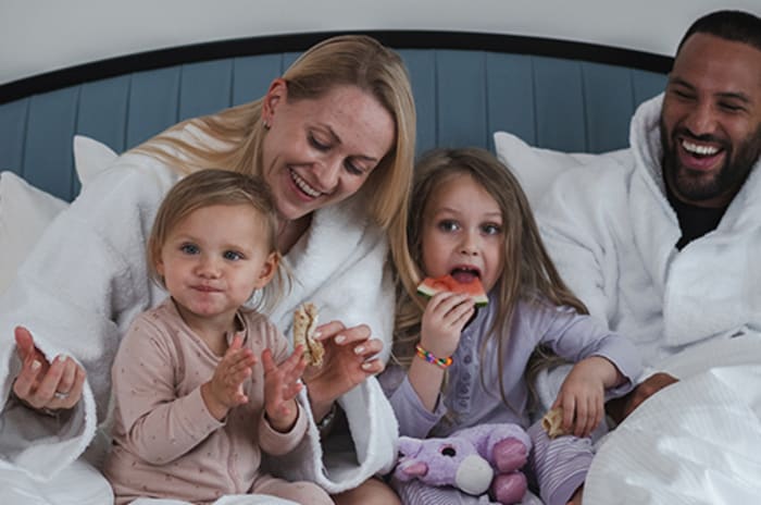 En familj som äter frukost i sängen på ett hotell