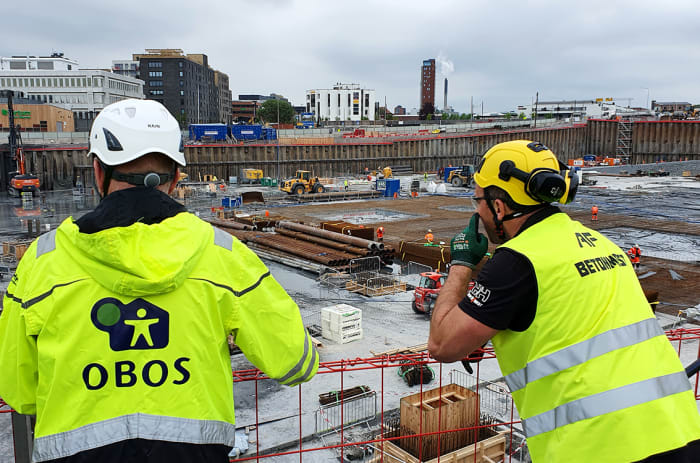 To byggearbeidere skuer ut over byggeplassen til Construction City