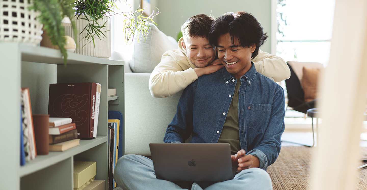 Ungt par ser på laptopskjerm og smiler